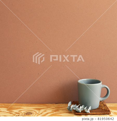 Gray mug cup with eucalyptus leaf on wooden table. brown wall background. copy space Gray mug cup with eucalyptus leaf on wooden table. brown wall background. copy space 81950642
