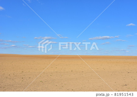 View of a deserted sand field against a blue sky with clouds. 81951543