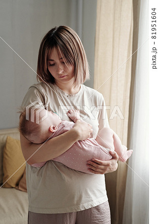 Young blond woman in t-shirt cradling her baby daughter 81951604