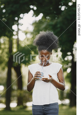 Portrait of a smiling young african-american girl holding a blue drink in a park 81954675