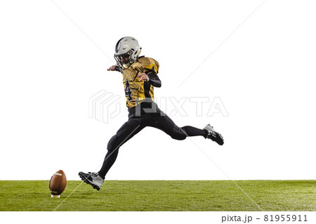 One professional american football player in special uniform kicking ball with leg isolated over white grass flooring background One professional american football player in special uniform kicking ball with leg isolated over white grass flooring background 81955911