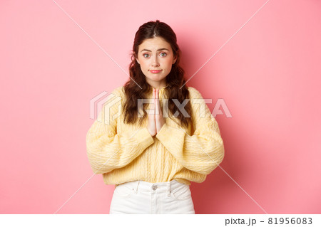 Please. Cute lady asking for favour, begging you, holding hands in pleading gesture and gazing at camera, standing over pink background Please. Cute lady asking for favour, begging you, holding hands in pleading gesture and gazing at camera, standing over pink background 81956083