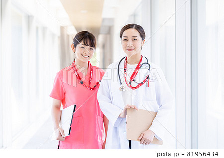 白衣を着た女医とピンクのスクラブを着る看護師の写真素材