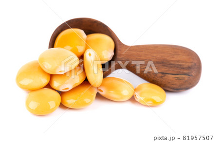 Pickled yellow lupine beans in wooden spoon, isolated on white background. Tournus, preserved lupinus. 81957507