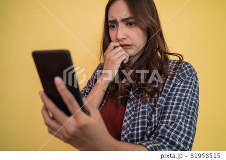 close up of asian woman looking at screen while using a smartphone with worried expression 81958515