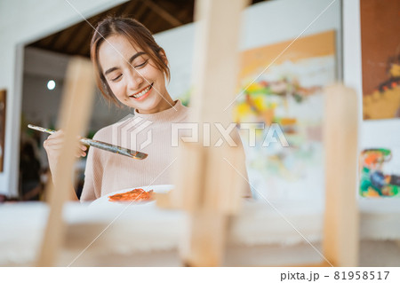 asian female artist painting on canvas doing some art projects on her studio workshop 81958517