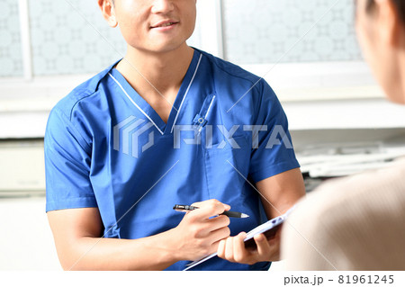 問診をするスクラブを着た若い男性の医療従事者（医師・ドクター） 81961245