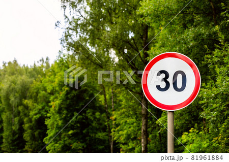 Road sign speed limit 30 kilometers per hour on green forest background with selective focus Road sign speed limit 30 kilometers per hour on green forest background with selective focus 81961884