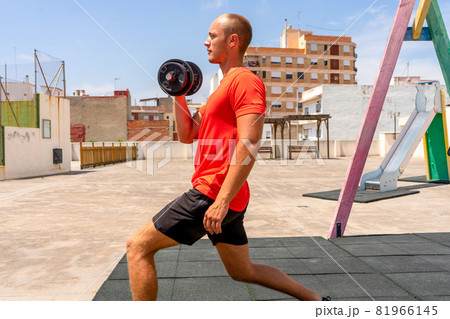 A young sexy athlete with perfect abs undresses on the street during the sunset. Healthy lifestyle, proper nutrition, training programs and nutrition for weight loss. 81966145