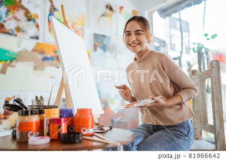 asian female painter painting on canvas in her workshop 81966642