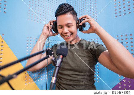 happy asian man is recording a podcast in his studio 81967804