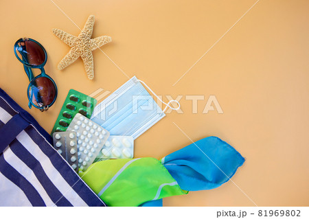 Beach bag, women's accessories, pills, syringe and protective medical mask on beige background. Beach bag, women's accessories, pills, syringe and protective medical mask on beige background. 81969802