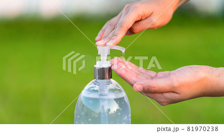 Closeup Asian woman hand using wash hand sanitizer gel pump dispenser before work over photo blurred of green color of grass while Coronavirus Network Outbreak, health care and covid19 concept 81970238