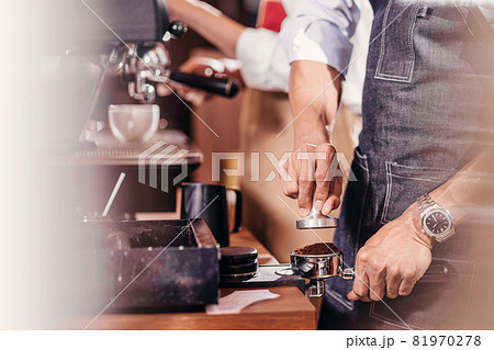 Closeup Asian Barista tamping the portafilter and preparing cup of coffee, espresso with latte or cappuccino for customer order in coffee shop, Small business owner and startup in coffee shop concept. Closeup Asian Barista tamping the portafilter and preparing cup of coffee, espresso with latte or cappuccino for customer order in coffee shop, Small business owner and startup in coffee shop concept. 81970278