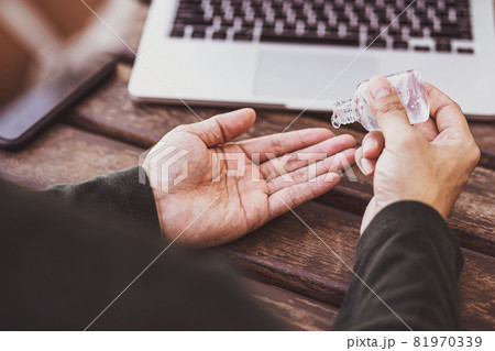 Rear view of Asian man doing hand sanitizer pumping alcohol gel before working with technology laptop, Working from home in Covid-19 pandemic, social distance and responsibility concept 81970339