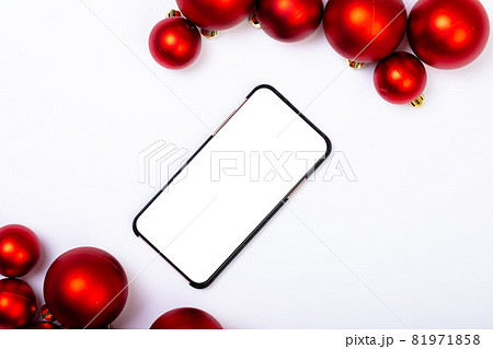 Composition of smartphone with copy space and red baubles on white background Composition of smartphone with copy space and red baubles on white background 81971858