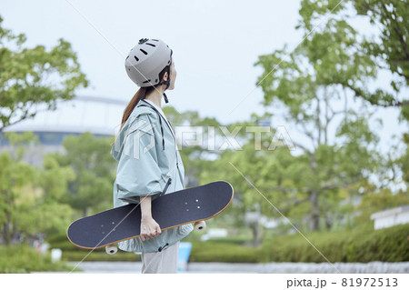 公園でヘルメットをかぶりスケートボードを持つ横向きの女性 公園でヘルメットをかぶりスケートボードを持つ横向きの女性 81972513