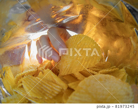 Hand taking potato chips inside the bag 81973245