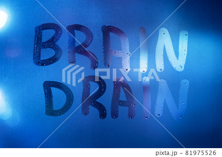 the words brain drain written on night wet window glass close-up with blurred background in classic blue color the words brain drain written on night wet window glass close-up with blurred background in classic blue color 81975526