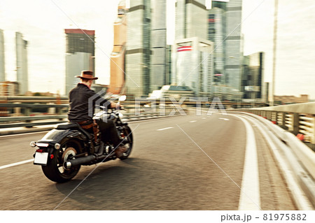 young man riding big bike ,motorcycle on city road against urban and town building scene 81975882