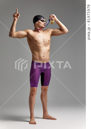 Young professional swimmer man indicates with fingers up showing a blank space. Young professional swimmer man indicates with fingers up showing a blank space. 81975976