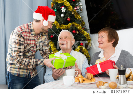 Parents and son exchanging Christmas gifts Parents and son exchanging Christmas gifts 81975977