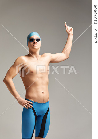 Young professional swimmer man indicates with fingers up showing a blank space. Young professional swimmer man indicates with fingers up showing a blank space. 81976000