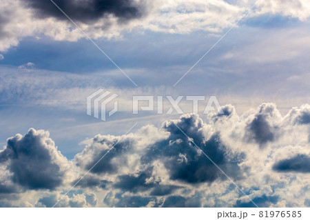 distant misty backlit cumulus and feather clouds near horizon closeup telephoto shot with polarizing effect. 81976585