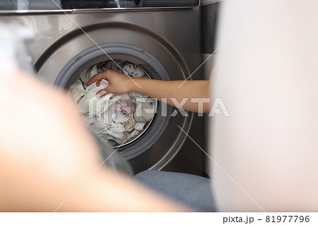 Female hand pulling out clean linen from washing machine closeup Female hand pulling out clean linen from washing machine closeup 81977796