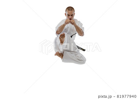 In a jump. Portrait of one caucasian sportsman training isolated over white background. Karate, judo, taekwondo sport In a jump. Portrait of one caucasian sportsman training isolated over white background. Karate, judo, taekwondo sport 81977940