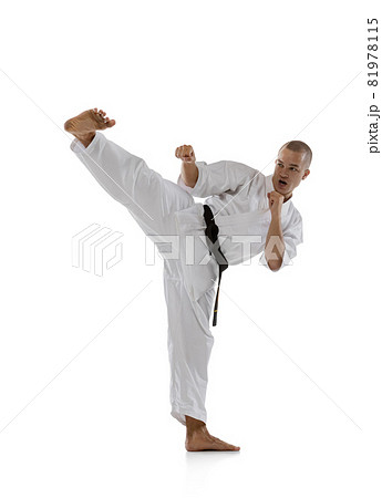Full-length image of one professional sportsman standing in side kick pose isolated over white background. Karate, judo, taekwondo sport 81978115
