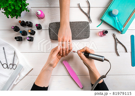 Manicure for the client. Close-up of the hands of a manicurist and client on a wooden background 81979115