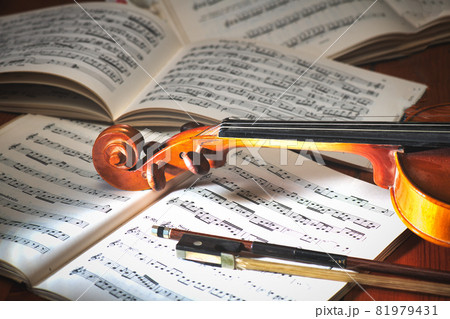 Violin with bow resting on musical score 81979431