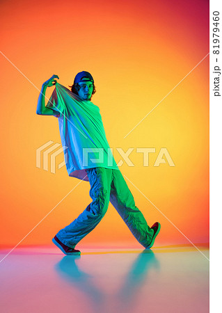 Conceptual portrait of young man, hip-hop dancer in stylish clothes in action isolated on colorful background at dance hall in neon light. 81979460