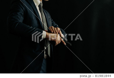拳銃を構えるスーツの人物 81981844