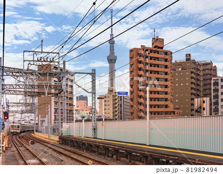 [東京・鐘ケ渕] 鐘ケ渕駅の線路で通過する東武伊勢崎線の電車と背景に東京スカイツリー。 81982494