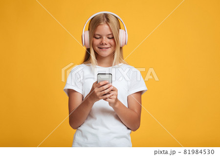 Smiling young european lady in white t-shirt in wireless headphones listen music, watch video 81984530