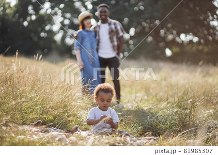 Diverse parents looking at son that playing on summerfield 81985307