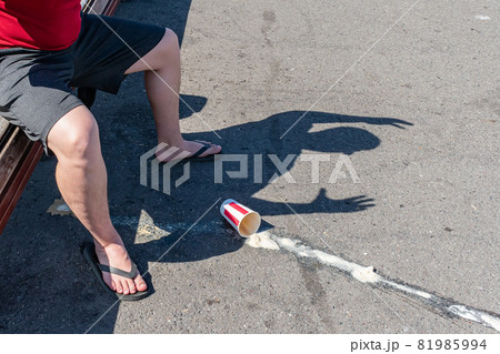 Spilled coffee on the road and the shadow of an angry man sitting on a bench Spilled coffee on the road and the shadow of an angry man sitting on a bench 81985994