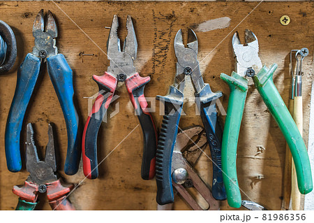 Set of pliers and nippers tools hanging on a wall 81986356