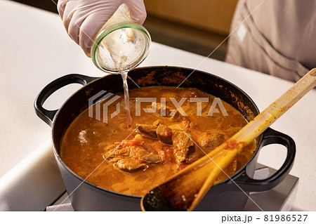 Hands pouring water in beef soup at the kitchen Hands pouring water in beef soup at the kitchen 81986527
