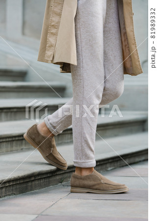 Portrait of fashionable women in beige pants and trench coat posing on the stone stairs Portrait of fashionable women in beige pants and trench coat posing on the stone stairs 81989332
