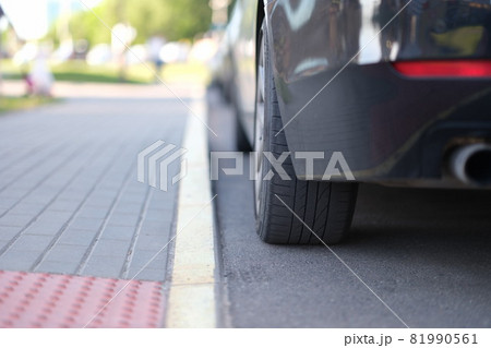 Car is parked near yellow median strip closeup 81990561