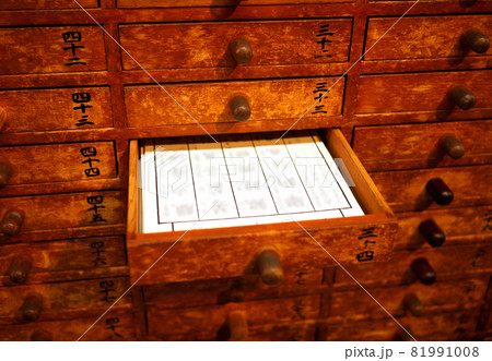 元旦の初詣の神社にてレトロな古いおみくじ入れの引き出しを開けて該当する番号のおみくじをもらう風景 81991008