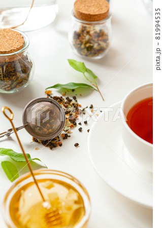 Cup of hot black tea on white table with dry tea jar 81994535