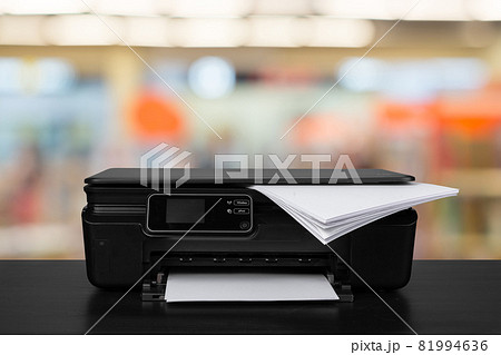 Compact laser printer on black desk against blurred background Compact laser printer on black desk against blurred background 81994636