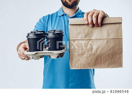 Unrecognizable man in blue polo with food delivery orders against grey background 81996548