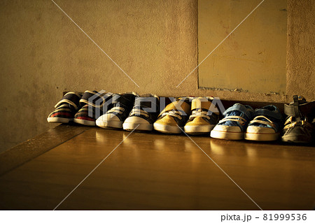 夕暮れの光が当たる玄関に並ぶ子供靴 81999536