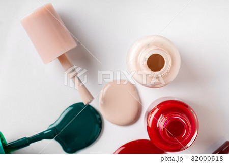 Nail polishes spilled out of bottles on white background 82000618
