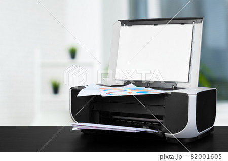 Compact laser printer on black desk against blurred background 82001605